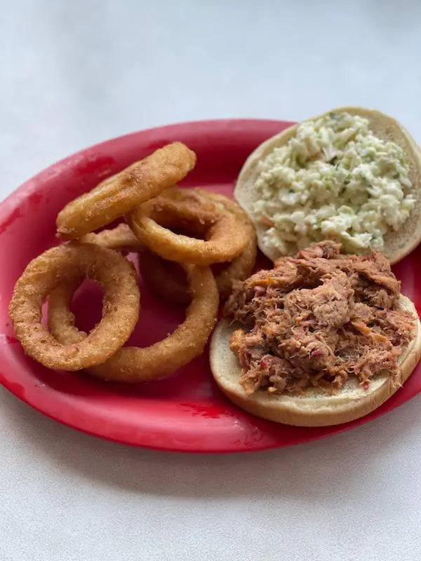 Pulled pork sandwich with onion rings.