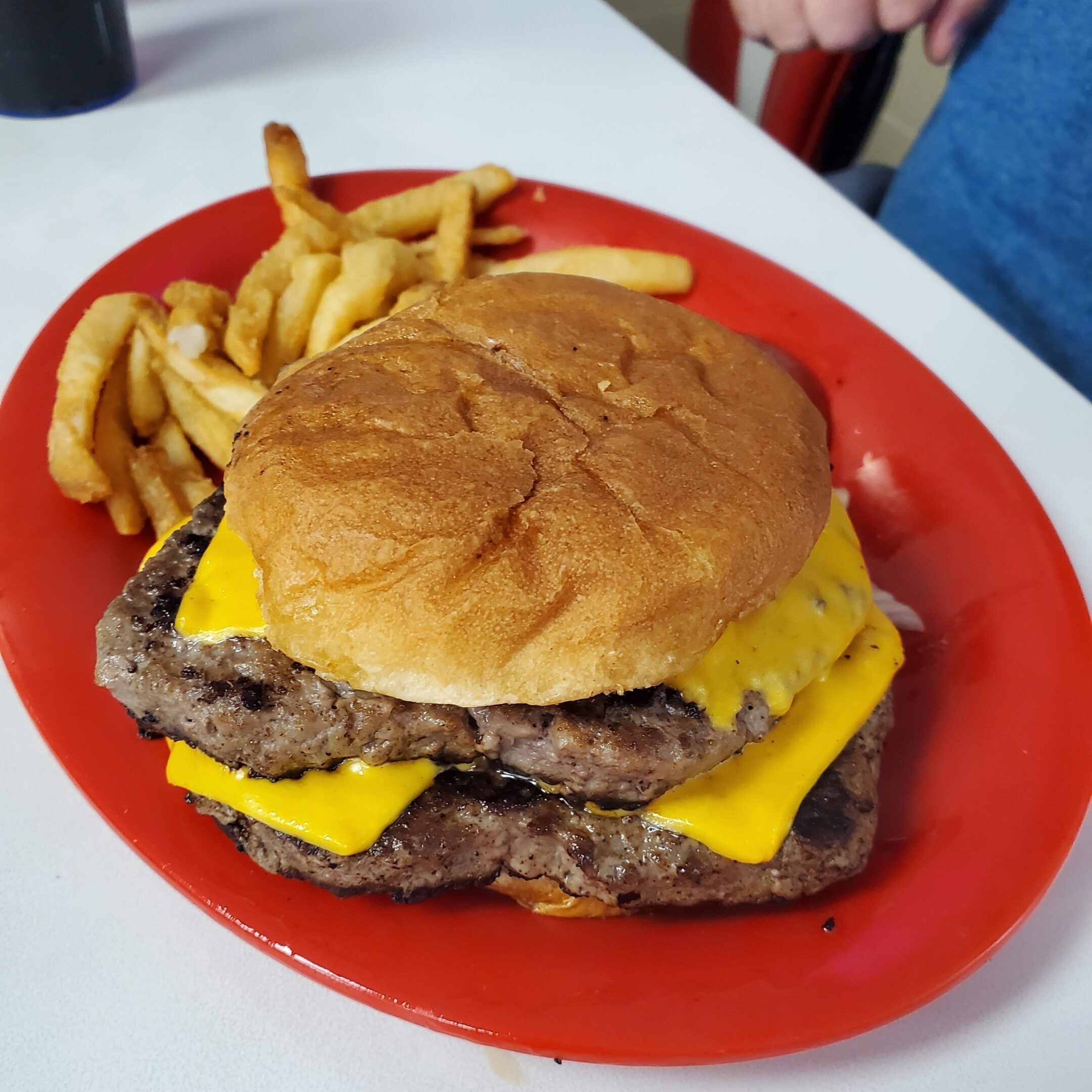 Cheeseburger with curly fries on plate.